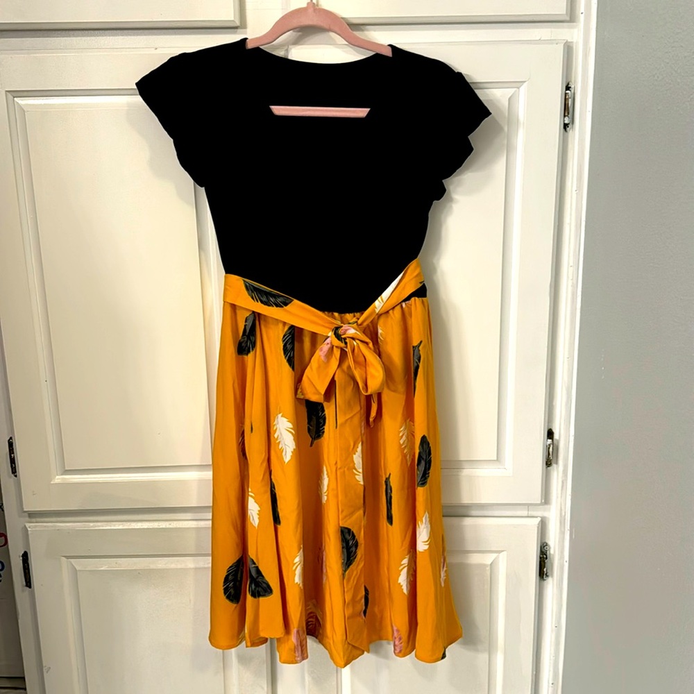 Black knit v-neck dress with gold bottom & black and white feathers